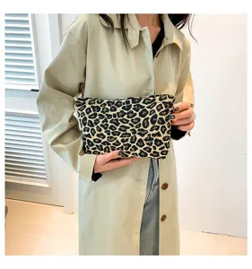Stilvolle Kosmetiktasche mit Leopardenmuster, getragen von einem Model im Trenchcoat.
