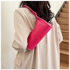 Detailed shot of a bright pink crocodile pattern underarm bag with a knotted strap detail