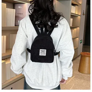 Stylish black corduroy mini backpack for women shown on a model in a cozy library
