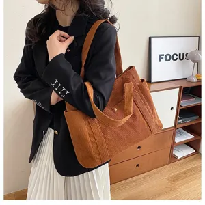 Vista dettagliata della borsa tote in velluto a coste marrone su un modello in un ambiente interno