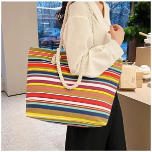 Model met een grote canvas draagtas in etnische stijl met kleurrijke strepen en touwhandvatten