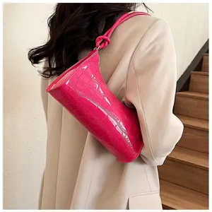 Detailed view of fuchsia croc-embossed armpit bag worn with a beige blazer coat