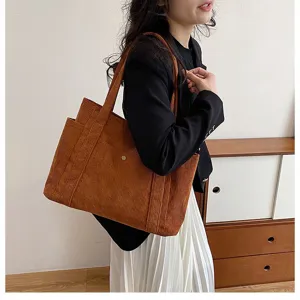 Foto lifestyle di una grande borsa tote in velluto a coste marrone portata a spalla