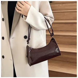 Close-up of a stylish dark brown croco-textured baguette bag on a model's shoulder.