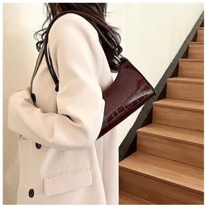 Detail of a chic burgundy stone texture underarm bag on a model in a beige blazer