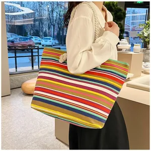 Grote kleurrijke gestreepte canvas tote tas gedragen op de schouder van het model.