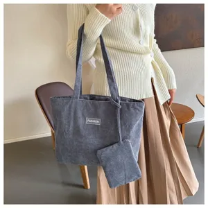 Vista detallada del bolso de pana gris con etiqueta de moda usado por la modelo