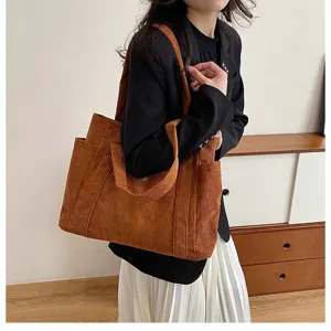 Borsa tote grande in velluto a coste marrone indossata da una modella in interno