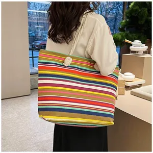 Detailopname van een model met een kleurrijke etnische gestreepte canvas draagtas.