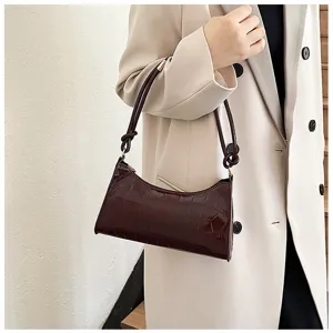 Detail view of a glossy burgundy stone pattern underarm bag on a model's shoulder.