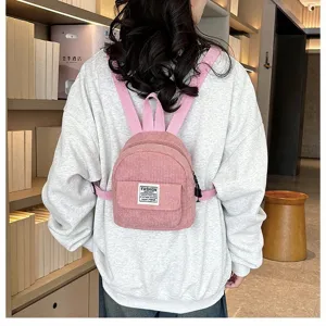 Detailed back view of a stylish pink corduroy mini backpack worn for casual travel