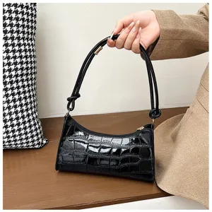 Detailed macro view of black crocodile-textured underarm bag with elegant knot strap