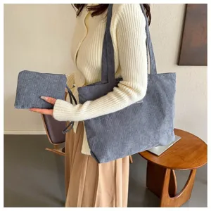 Vista detallada de un conjunto de bolso tote de pana gris con neceser a juego en una modelo