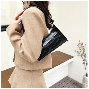 Elegant black crocodile-texture underarm bag carried by a model in a beige suit