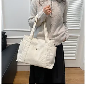 Grande borsa tote in velluto a coste crema indossata da una modella per lo stile.