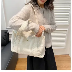 Donna che indossa una grande borsa tote in velluto a coste beige per un look casual