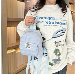 Close-up of light blue corduroy mini backpack with front pocket and fashion label.