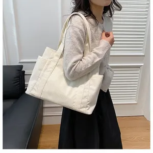 Foto lifestyle di una grande borsa tote in velluto a coste bianco portata da una modella.
