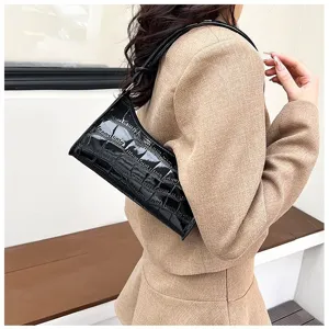 Detail view of a black stone pattern minimalist underarm bag carried with a beige suit