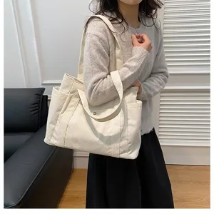 Vista dettagliata di una borsa tote in velluto a coste bianco tenuta da una donna in abito casual