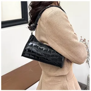 Detail view of a black crocodile pattern underarm bag styled with a professional beige suit