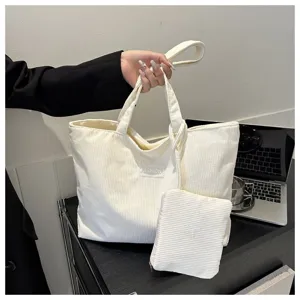 Bolso tote de pana blanca minimalista con un pequeño estuche a juego sostenido en la mano
