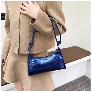 Detail view of the shiny blue stone-patterned underarm shoulder bag worn by model