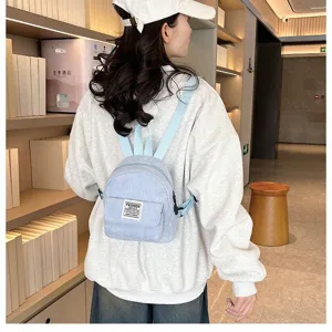 Detailed back view of a minimalist light blue corduroy mini backpack worn by model