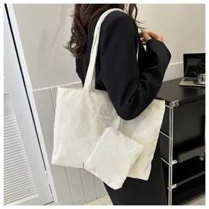 Vista detallada de un bolso tote grande de pana crema con una bolsa pequeña a juego