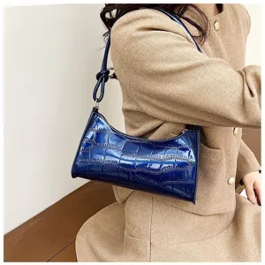 Detail view of a stylish blue crocodile pattern underarm bag worn with a tan blazer