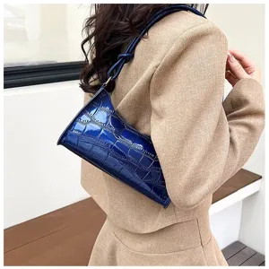 Detail shot showing the glossy crocodile-embossed texture of the blue underarm bag.