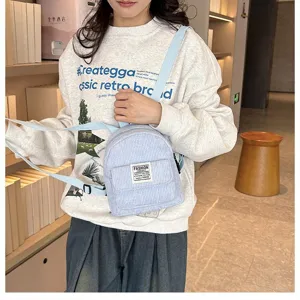 Model wearing a light blue corduroy mini backpack in a stylish indoor setting.
