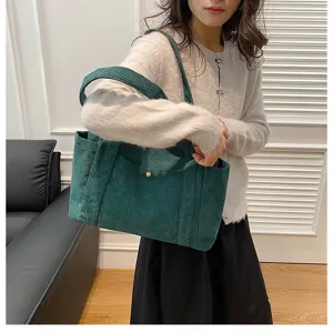Dettaglio della borsa tote in velluto a coste verde con texture e bottone in metallo.