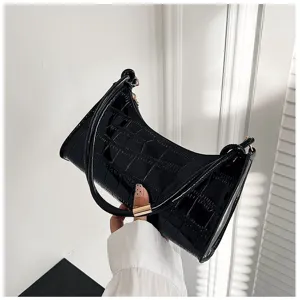 Detailed view of the glossy black faux crocodile skin texture on a stylish underarm bag