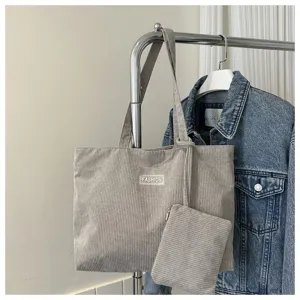 Detalle de bolso tote de pana gris con pequeña bolsa a juego en un perchero