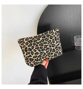 Detailansicht einer stilvollen Kosmetiktasche mit Leopardenmuster, die zur Größe gehalten wird