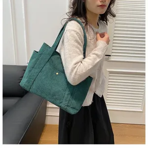 Vista dettagliata di una borsa tote in velluto a coste verde portata da una modella