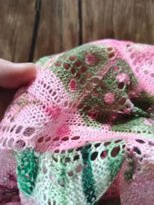 Vista macro dettagliata di un maglione a maglia traforata con vivaci motivi floreali 3D.