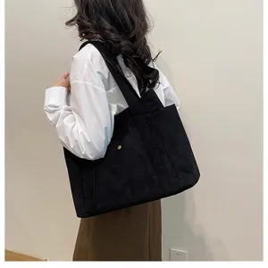 Modella con borsa tote in velluto a coste nera con trama a coste e design spazioso