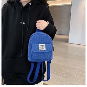 Close-up detail of a stylish blue corduroy mini backpack for women with fashion tag