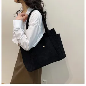 Primo piano di un'elegante borsa tote in velluto a coste nero indossata da una modella