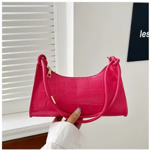 Detail of a vibrant pink stone-patterned underarm bag with elegant gold zipper hardware.