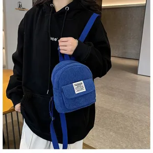 Small blue corduroy backpack styled as a shoulder bag on a model for casual daily use