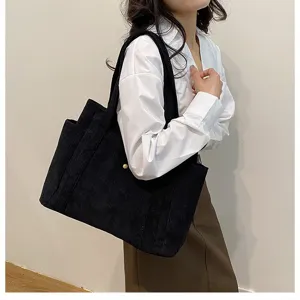 Dettaglio di una borsa tote in velluto a coste nera di grande capacità portata a spalla