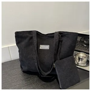 Primer plano detallado del bolso tote de pana negra con su estuche a juego