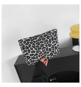 Handgehaltene Clutch-Tasche mit Leopardenmuster zeigt detailliertes Muster und Textur