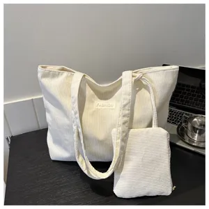 Detalle de primer plano de la tela de pana crema en el conjunto de bolso tote y estuche.