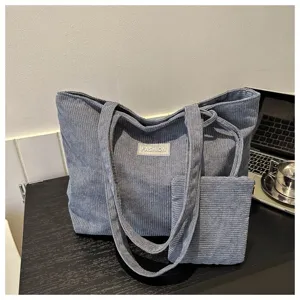 Detalle de un bolso tote grande de pana azul con un pequeño neceser a juego en la oficina