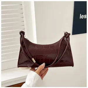 Detailed close-up of dark burgundy crocodile texture on a chic patent leather underarm bag