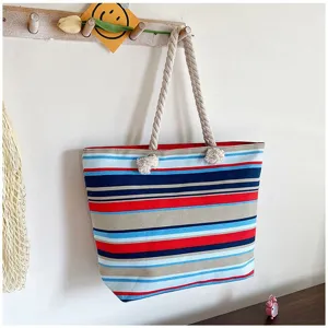 Detailweergave van een kleurrijke gestreepte canvas tas met touwhandvatten aan de muur.